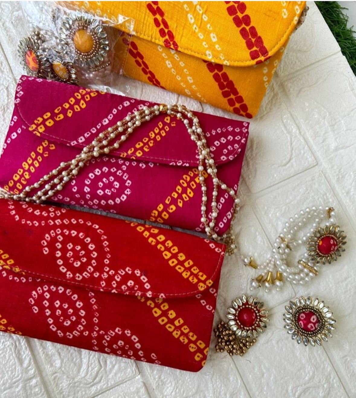Bandhani print potli clutch with pearl chain paired with matching kundan jewelry set for wedding and festive wear